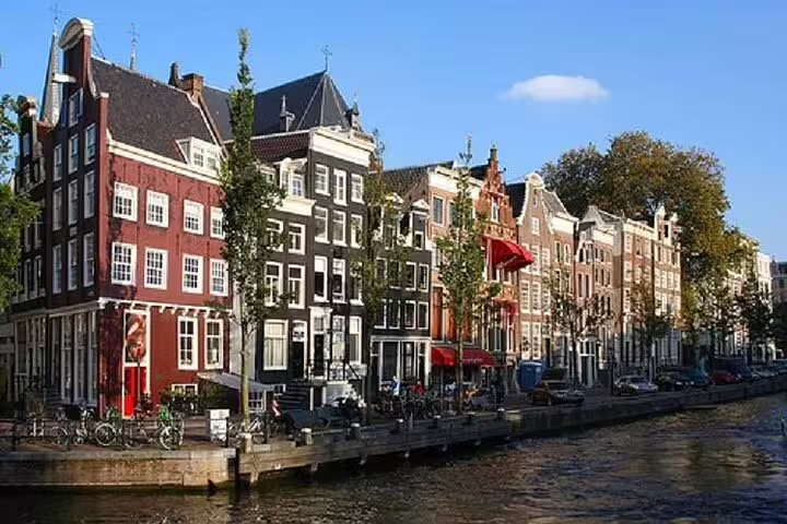 Colorful Dutch canal houses along Amsterdam's picturesque waterfront under a clear sky, perfect for a winter walking tour.