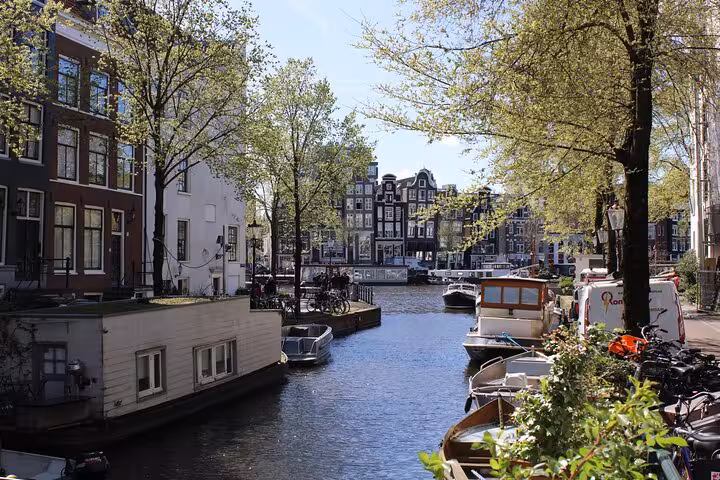 Amsterdam canal lined with houseboats and historic buildings on a private walking tour with a local guide
