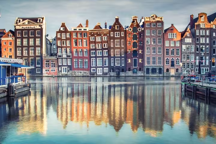 Amsterdam waterfront houses reflected in canal, perfect for VIP Schiphol Airport departure transfer service