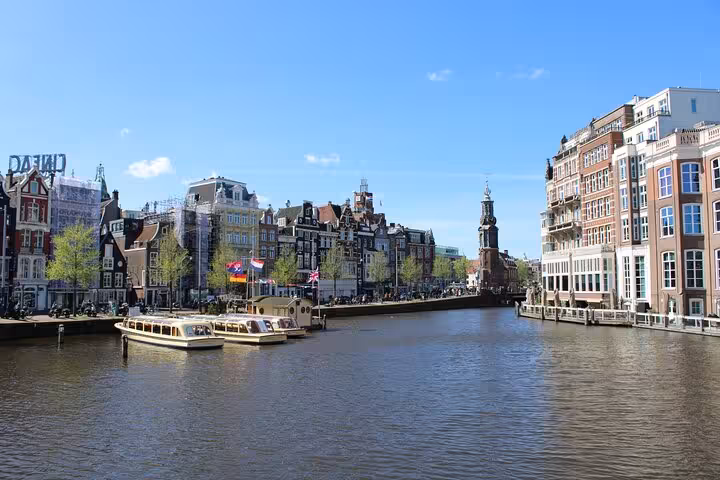 Amsterdam canal view with historic gabled houses and boats, ideal for a private city walking tour with a local guide