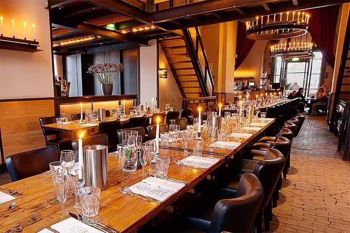 Elegant candlelit restaurant interior with long wooden dining tables set for a group dinner in Amsterdam
