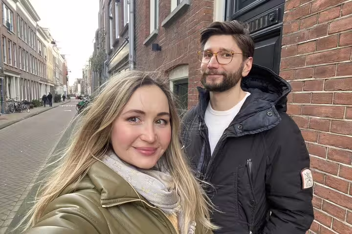 Couple taking a selfie on a historic Amsterdam canal street with brick buildings