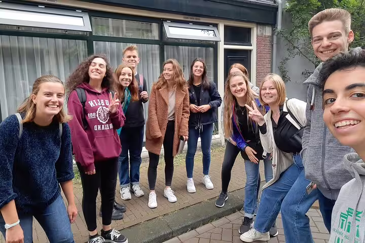 Group of smiling young tourists posing together on an Amsterdam city street during a walking tour
