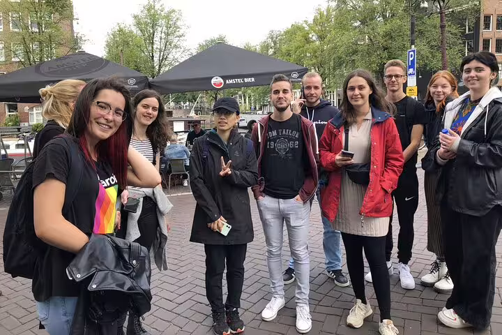 Group of young tourists posing together on a brick square in Amsterdam during a self-guided walking tour