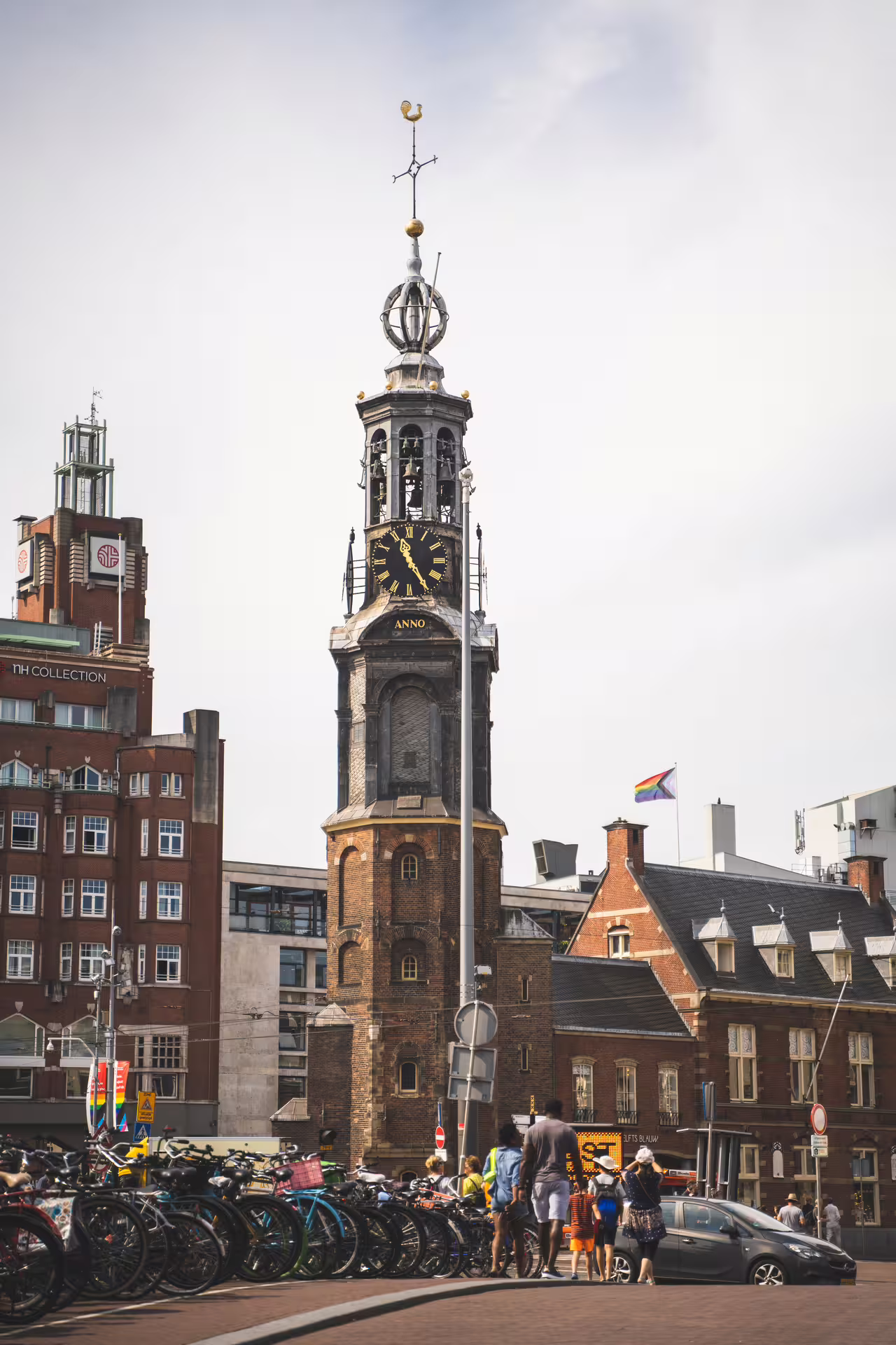 Historic Amsterdam clock tower and bustling street, ideal for a walking tour and canal cruise with unlimited drinks and cheese tasting.