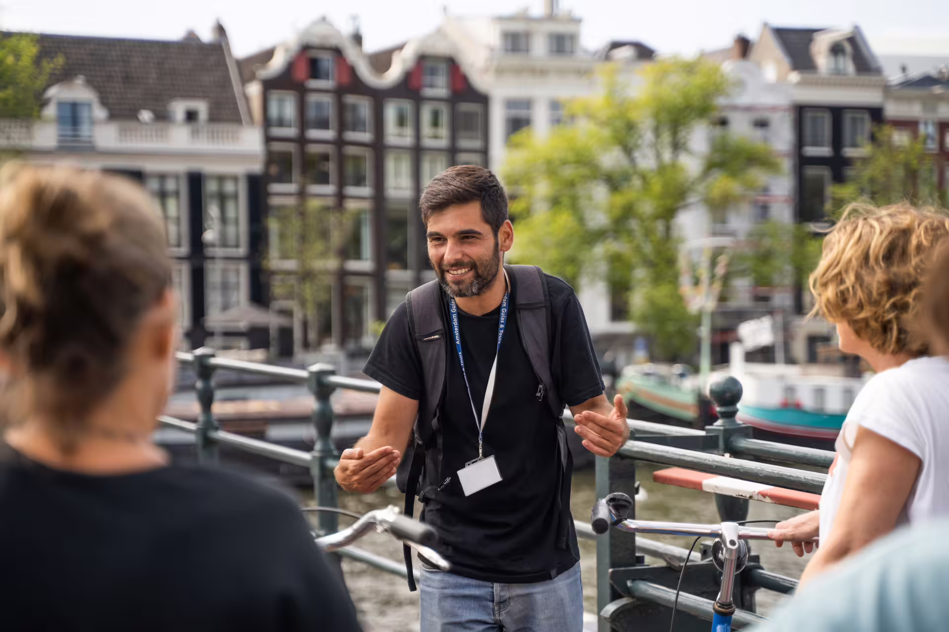 Tour guide leads Amsterdam countryside bike tour with scenic canal backdrop, enhancing the experience with local insights.