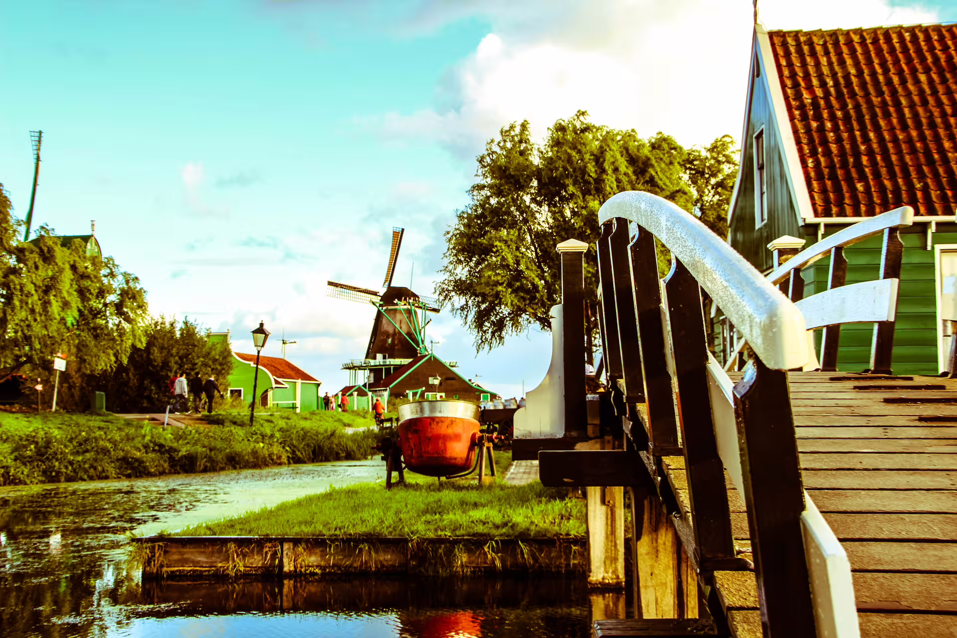 Scenic countryside bike tour with picturesque windmill, charming bridge, and lush greenery along a tranquil canal.
