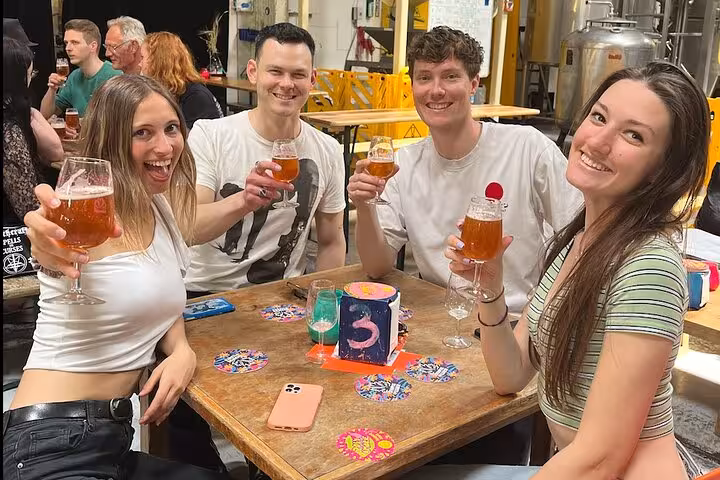 Friends raising craft beer glasses at Amsterdam brewery tasting stop on Brew Bus brewery tour