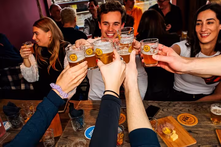 Guide pours Dutch craft beer flights at Amsterdam tasting tour, served with cheese and sausage pairings