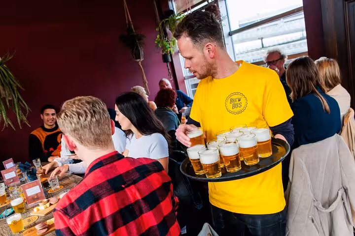 Guide serving Amsterdam craft beer flights to guests during guided tasting with cheese and sausage pairing