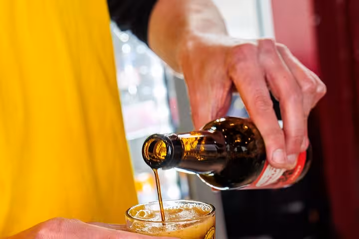 Guide pouring Dutch craft beer into a tasting glass during Amsterdam craft beer tour with cheese and sausage snacks