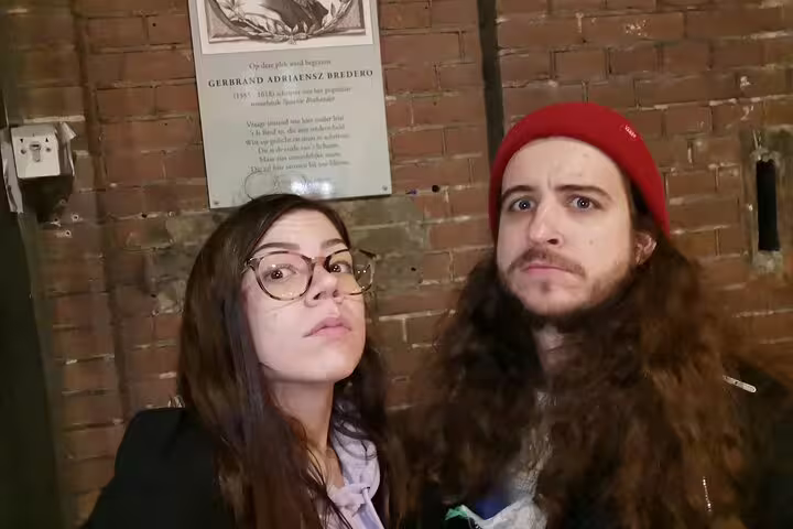 Two visitors reading a historic plaque on a brick wall during Amsterdam ghost walking tour