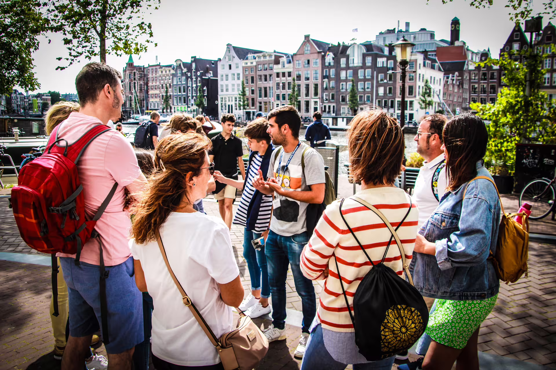 A small group of tourists enjoys a guided walking tour in Amsterdam, exploring historic canals and iconic architecture.