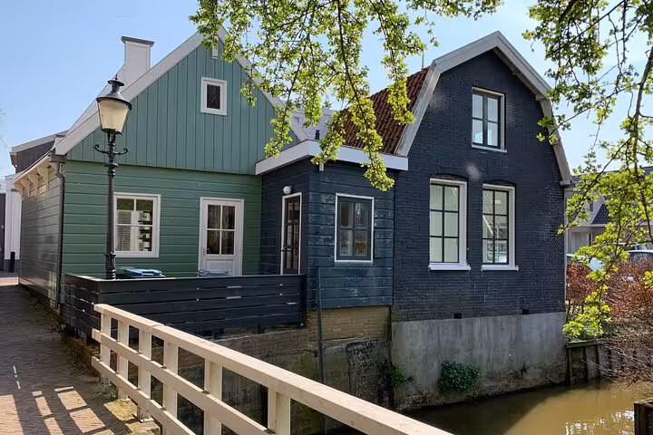 Traditional wooden houses beside a canal in a charming Dutch village, hidden gems tour from Amsterdam