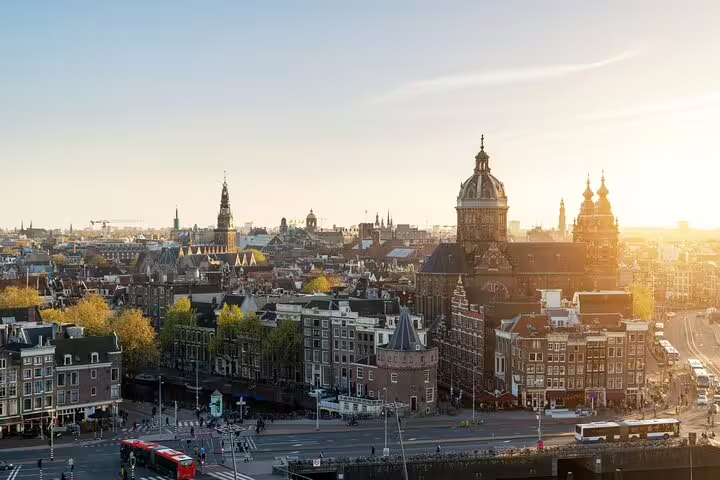 Aerial view of Amsterdam cityscape at sunset with historic buildings and church domes