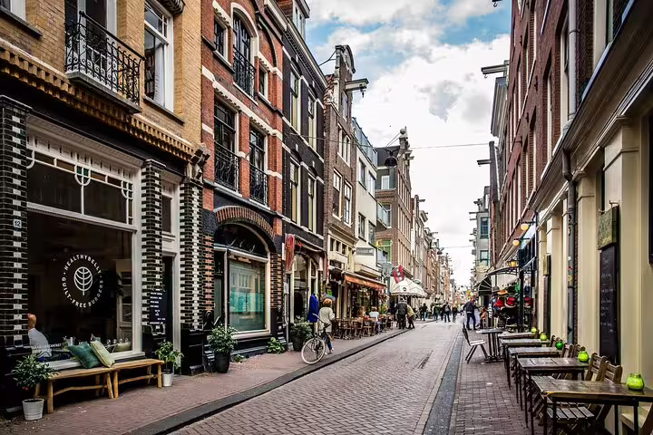 Narrow cobblestone street in Amsterdam Jordaan neighborhood with historic brick buildings and outdoor cafes