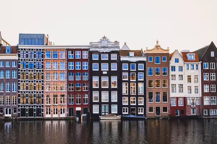 Colorful historic canal houses along Amsterdam's waterfront reflecting in calm water