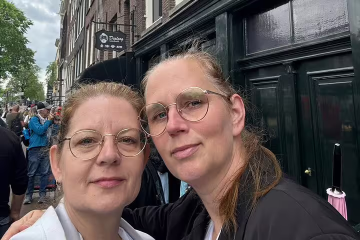Two women with glasses smiling together on a street in Amsterdam's Jordaan neighborhood
