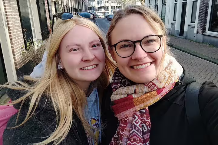 Two smiling women taking a selfie on a charming Amsterdam Jordaan neighborhood street