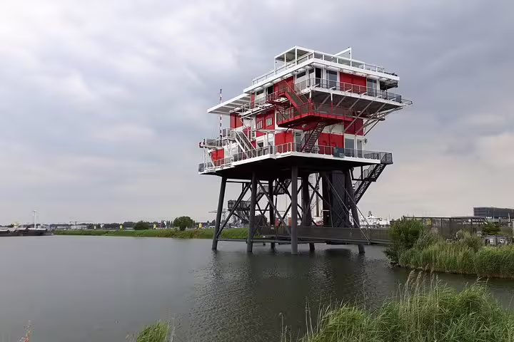 Red and white industrial building on the water in Amsterdam Noord, seen on a private guided bike tour
