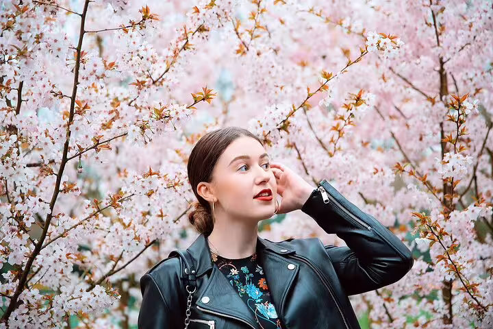 Private photoshoot tour in Amsterdam with woman in leather jacket posing among blooming cherry blossoms