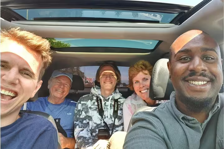 Group enjoying a private sightseeing tour in Amsterdam with a smiling guide in a comfortable vehicle.