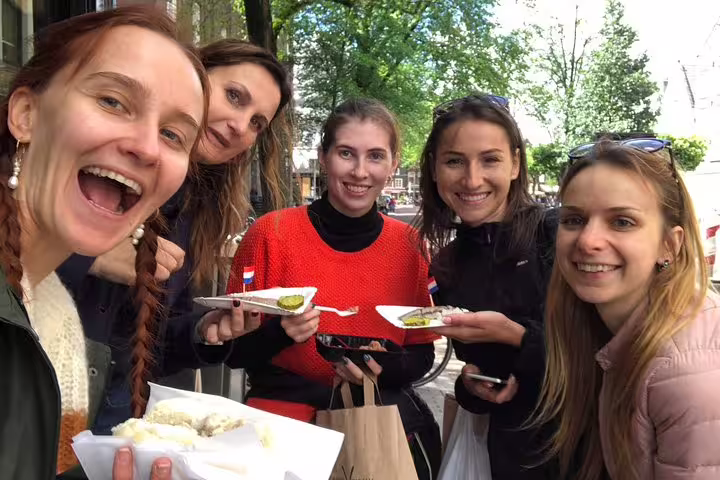 Friends tasting Dutch street snacks in Amsterdam, foodie stop on an unexpected treasures private walking tour