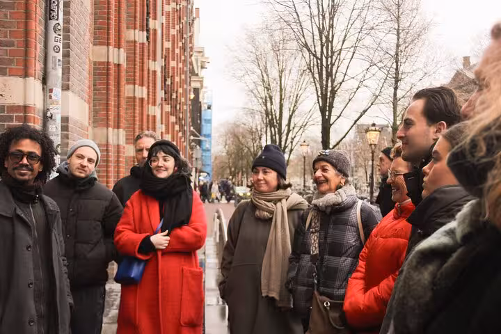Guests listening to a local guide on a customized Amsterdam private walking tour near a historic brick building