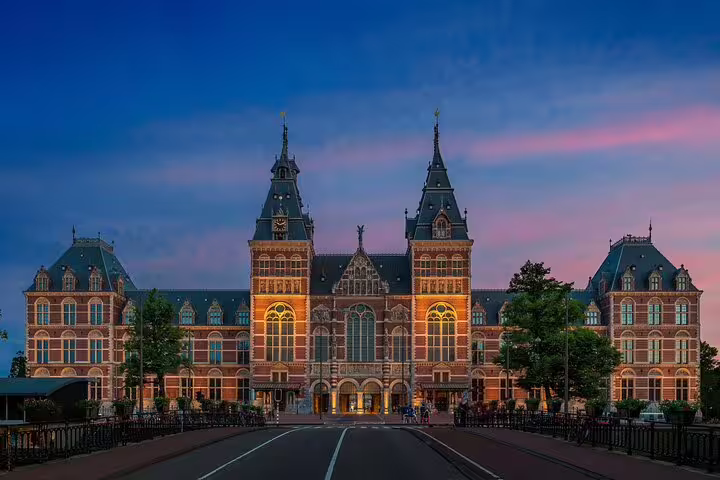 Rijksmuseum Amsterdam illuminated at dusk with ornate Dutch Renaissance brick facade and twin towers