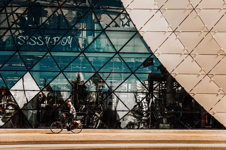 Cyclist outside glass facade in Amsterdam city center, pickup point for Amsterdam or Schiphol to Eindhoven transfer