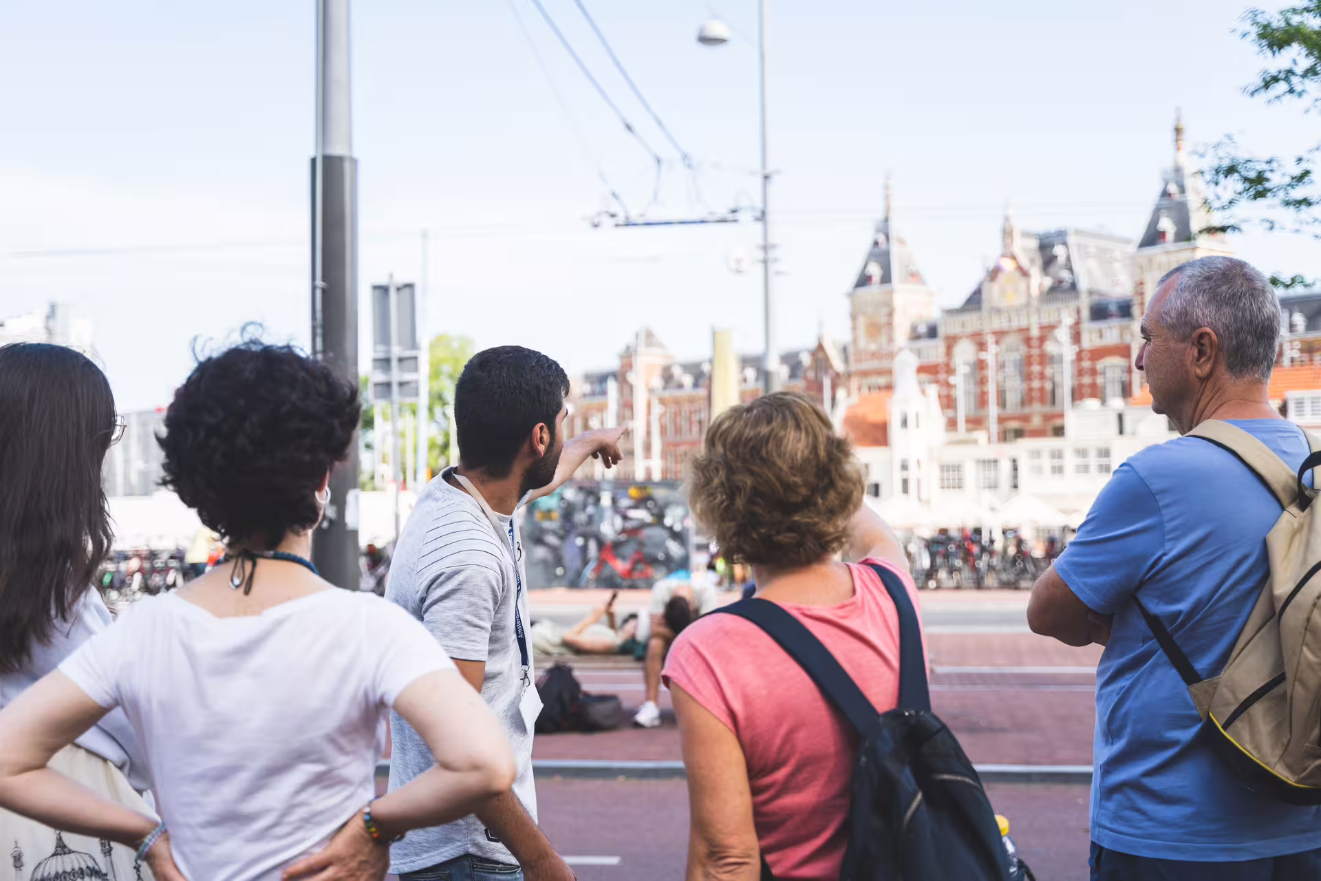 Tourists explore Amsterdam with a guide, enjoying a walking tour near historic architecture before a canal cruise.