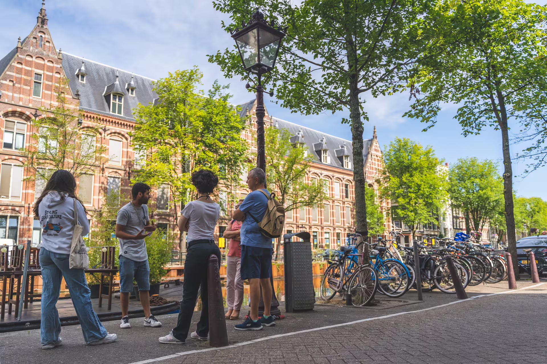 Group of tourists enjoying an Amsterdam walking tour with cheese tasting, surrounded by historic architecture and bicycles.