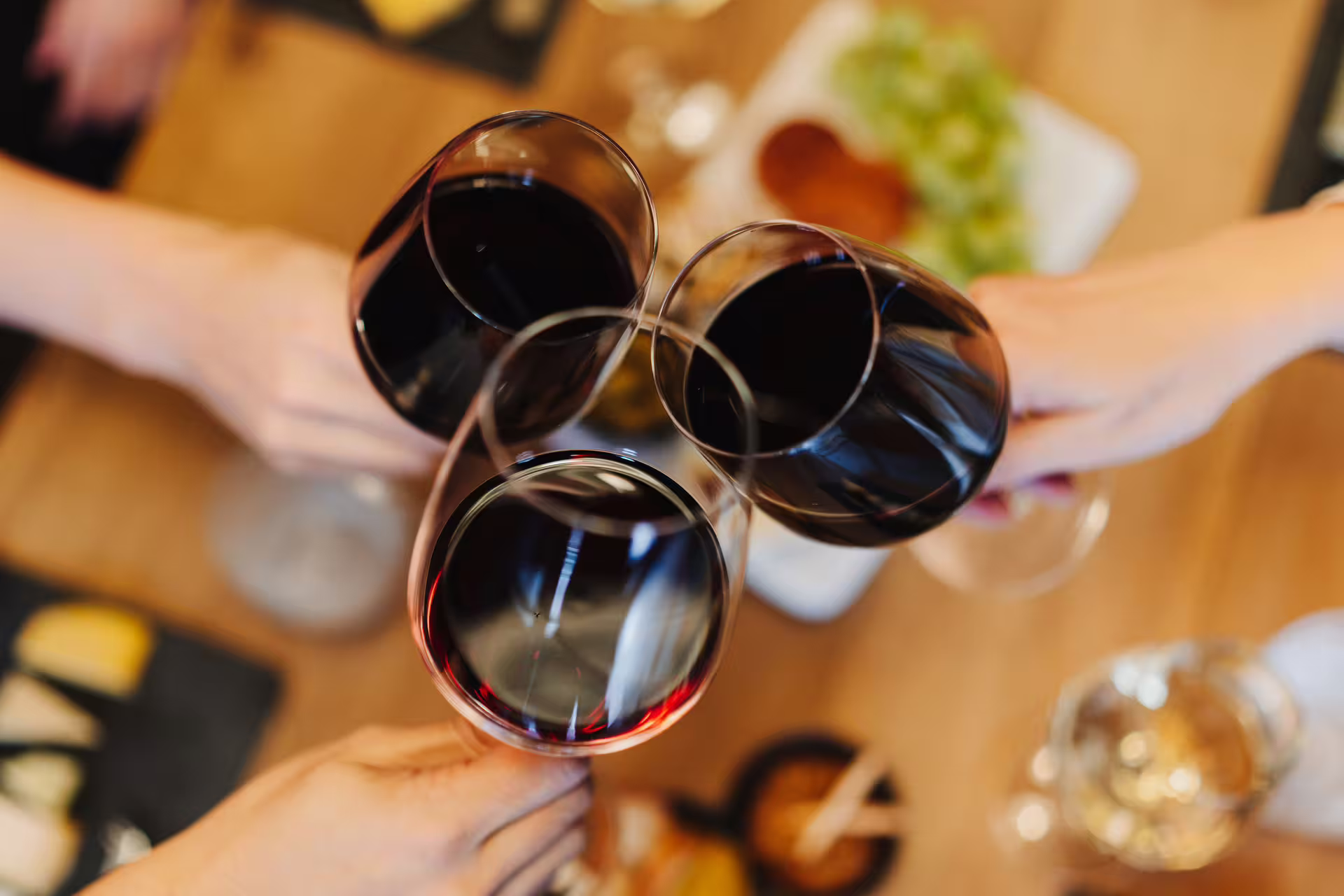 Four people clinking glasses of red wine over a table with cheese platters during an Amsterdam walking tour with cheese tasting.