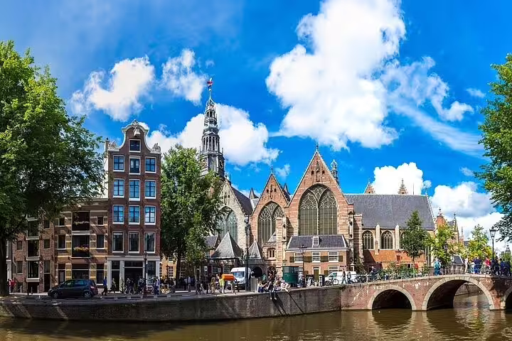 Scenic view of Amsterdam's historic Old Church and canal during a vibrant winter walk, perfect for exploring Dutch architecture.