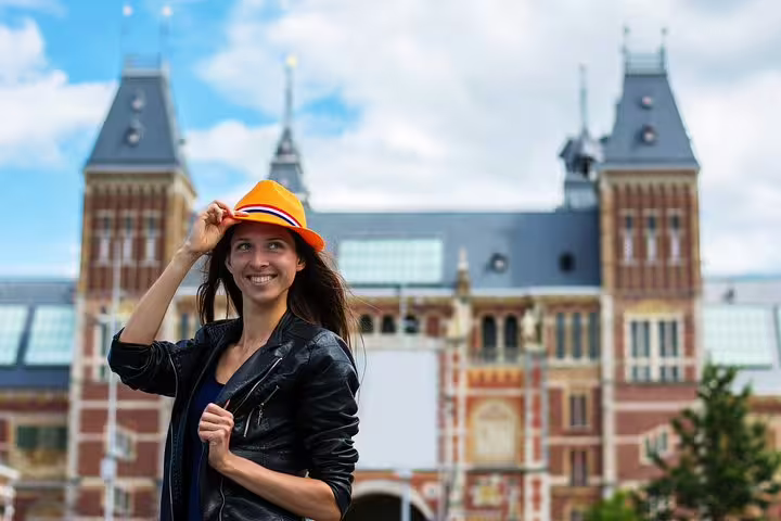 Woman in orange hat smiling in front of the Rijksmuseum, perfect for an Amsterdam winter walk tour experience.