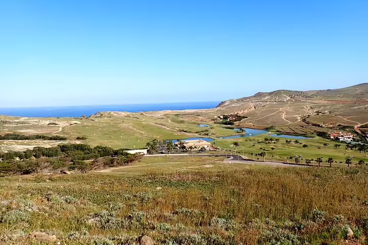 Expansive view of Ana Ferreira's lush landscapes, rolling hills, and distant ocean, perfect for a scenic caves and peaks trek.
