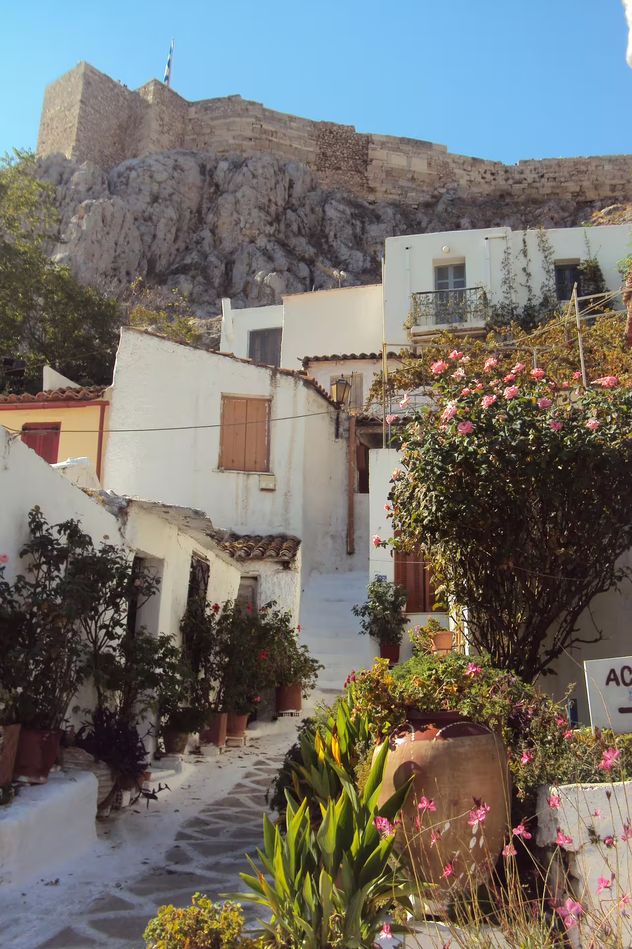 Anafiotika alley below the Acropolis rock with white houses and flowers on Plaka and Monastiraki walk