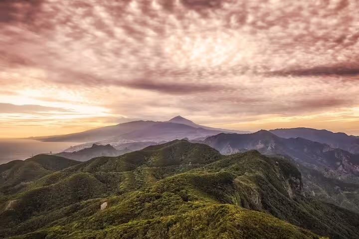 Breathtaking sunset over Anaga Tenerife mountains with lush greenery and dramatic clouds, ideal for nature tours.