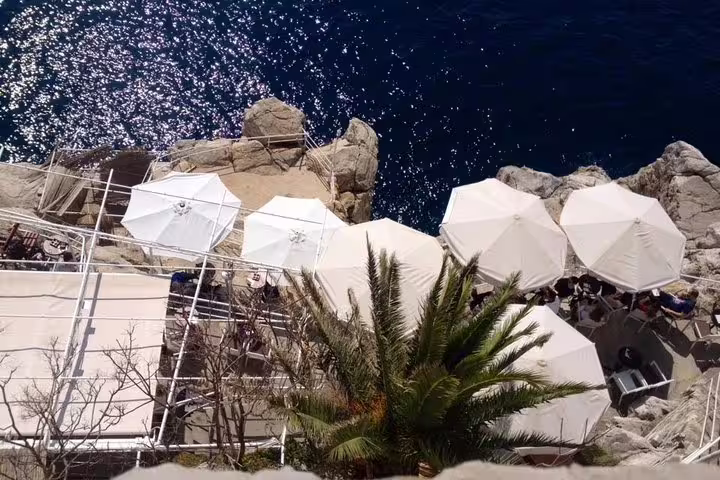 Seaside terrace by ancient city walls, rocky coast and umbrellas, scenic stop on wars walking tour