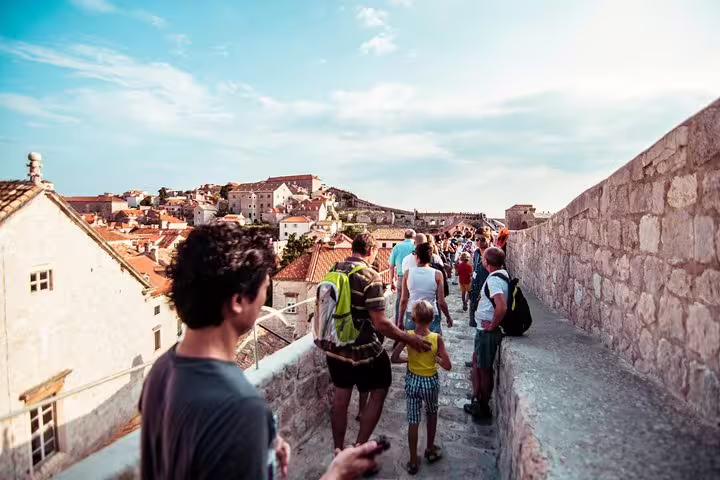 Walking tour group on ancient city walls with panoramic old town rooftops, historic fortifications and views