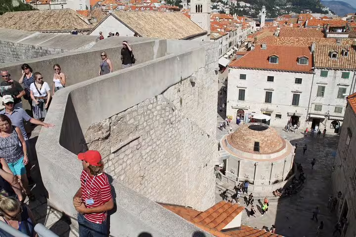 Visitors walking atop ancient city walls overlooking old town rooftops, immersive wars history tour