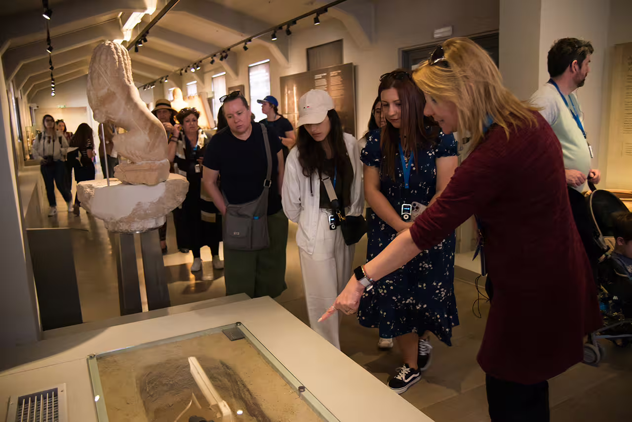 Visitors with guide viewing artifacts inside the Ancient Corinth Archaeological Museum on a Nafplion day trip