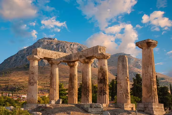 Ancient Corinth Temple of Apollo columns with mountain backdrop, stop on private full-day tour from Athens