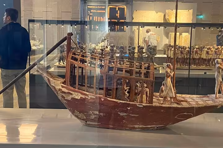 Ancient Egyptian wooden boat model exhibit at the Grand Egyptian Museum, part of Giza Pyramids day tour with lunch