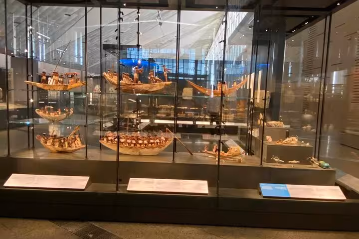 Glass case of ancient Egyptian boat models at the Grand Egyptian Museum, part of Giza Pyramids and lunch tour