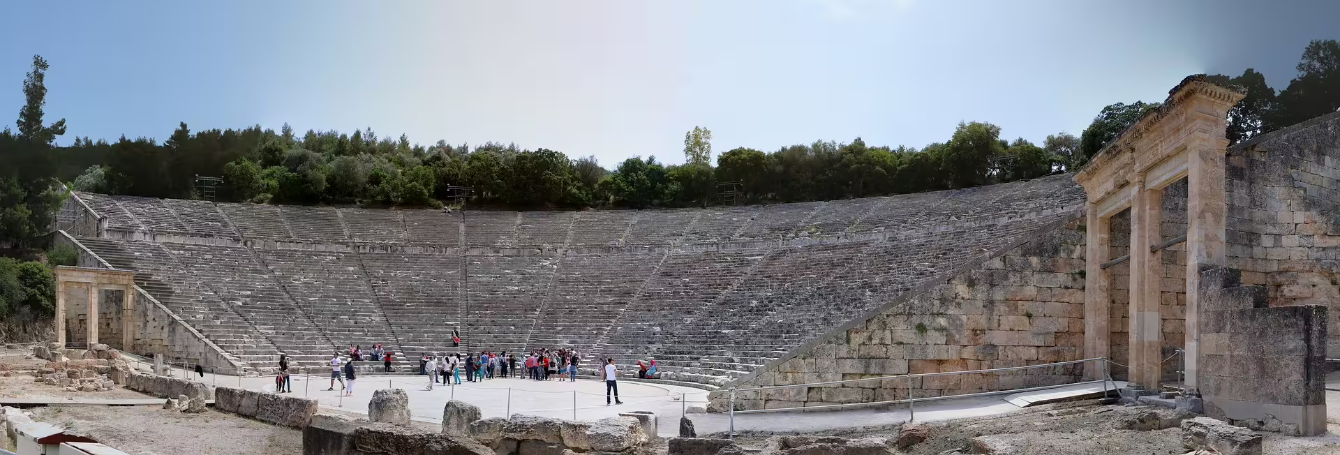 Ancient Epidaurus theater seating with visitors, included on private Classical Athens and Cape Sounio tour