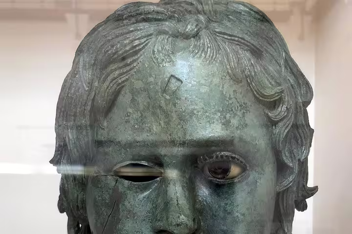 Close-up of ancient bronze statue head at Olympia Archaeological Museum on private guided day trip from Athens