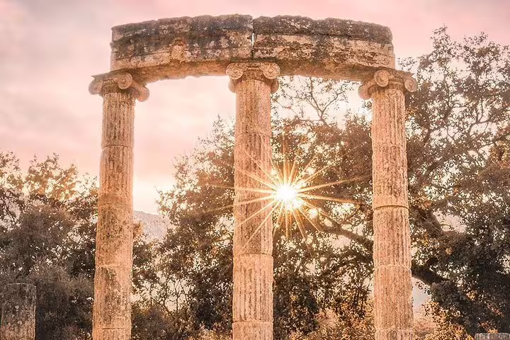 Temple columns at Ancient Olympia with sunburst at sunset, signature view on private full-day tour from Athens