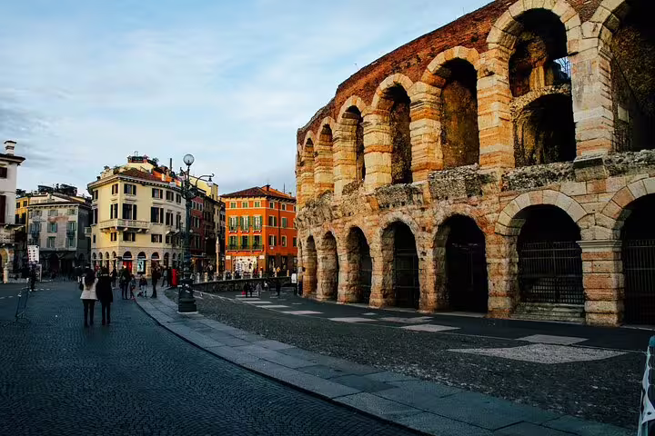 Ancient Roman arena exterior with arched stone walls in a historic Italian piazza