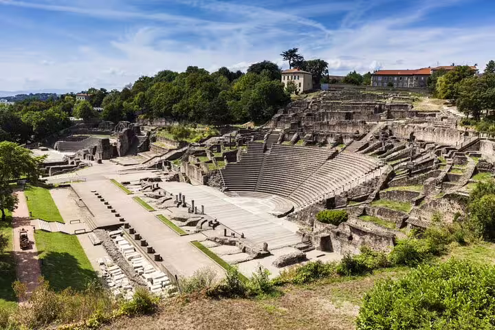 Ancient Roman theatre ruins in Lyon with stone seating tiers and stage area surrounded by green trees